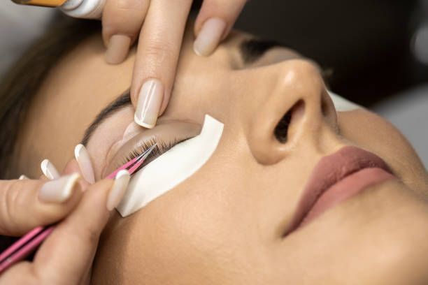 Lash lamination treatment in the salon Beautiful young woman with beautiful clean skin having a lash lift treatment. She is laying on the bed, her eyes are closed and the beautician is doing the treatment. picking up stock pictures, royalty-free photos & images
