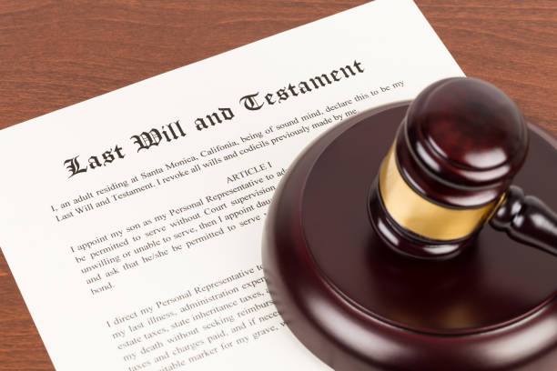 Last will and testament on yellowish paper with wooden judge gavel; document is mock-up stock photo