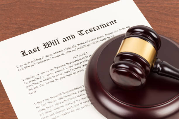 Last will and testament on yellowish paper with wooden judge gavel; document is mock-up stock photo