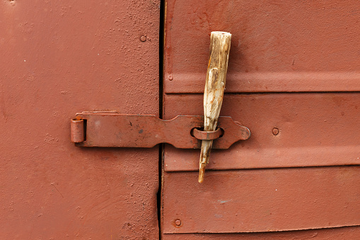 Old rusty iron door with the hinged lock and a latch.