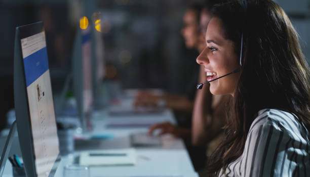 Late nights are just a part of the job Cropped shot of an attractive young female call center agent working late in the office with her colleagues in the background it support stock pictures, royalty-free photos & images