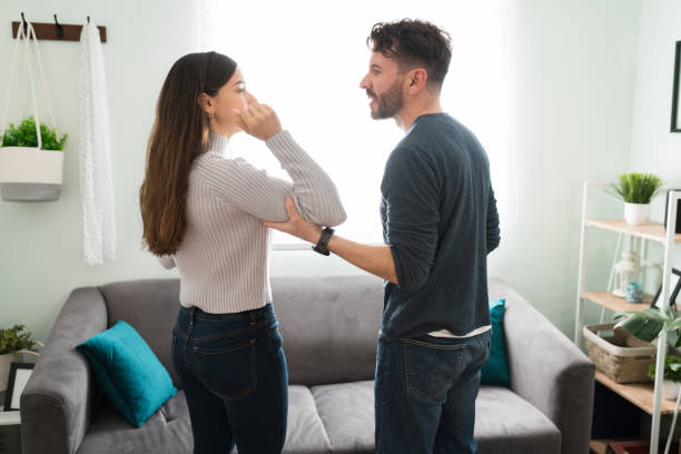 Latin couple with relationship and physical abuse problems Side view of an angry hispanic man in his 30s grabbing the arm of his young wife during a fight and discussion at home. Domestic violence concept domestic violence stock pictures, royalty-free photos & images