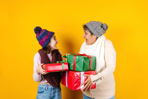 Latin family grandmother and granddaughter holding christmas gift on yellow background in Mexico Latin America Latin family grandmother and granddaughter holding christmas gift on yellow background in Mexico Latin America hot mexican girls stock pictures, royalty-free photos & images