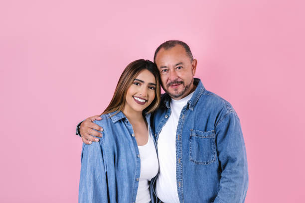 latin father and daughter in casual clothes in a copy space on pink background in Mexico Latin America stock photo