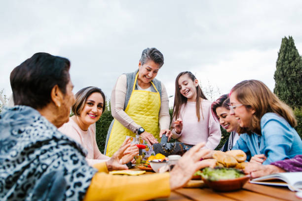latin grandmother and granddaughter, daughter cooking mexican food at home, three generations of women in Mexico stock photo