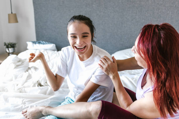 Latin mom and teenage daughter with cerebral palsy having fun on bed at home, in disability concept in Latin America stock photo