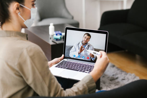 Latin woman talking with a doctor online using digital tablet and computer, feeling bad at home. Concept of telemedicine and patient in Mexico city stock photo