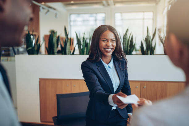 Laughing African American concierge talking with guests during check in stock photo