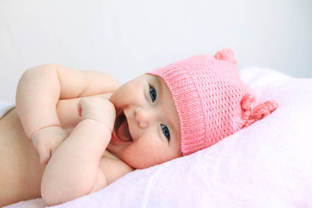 Laughing blue eyed baby with pink hat stock photo