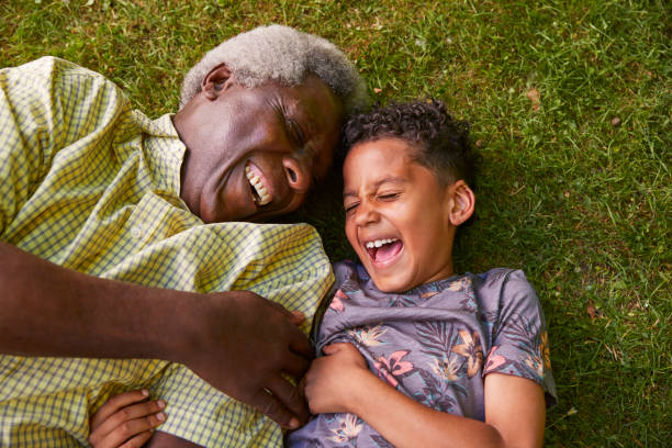 overhead skrattar pojke och farfar liggande på gräset, närbild - retirement overview bildbanksfoton och bilder