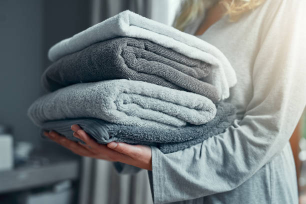 Laundry day Closeup shot of an unrecognizable woman carrying a pile of towels while doing laundry at home towel stock pictures, royalty-free photos & images