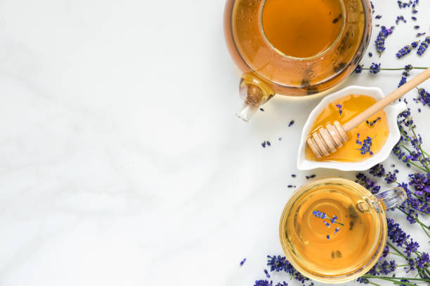 lavender tea in a cup and teapot with honey and fresh flowers over white marble table. herbal drink. top view lavender tea in a cup and teapot with honey and fresh flowers over white marble table. herbal drink. top view with copy space infused photos stock pictures, royalty-free photos & images