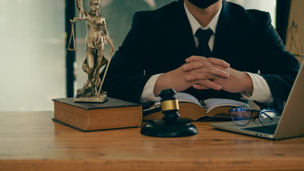 Lawyer Counsel Office work with contract documents and golden goddess scales with hammer on the table serve advice, justice and legal concept image with film grain effect.