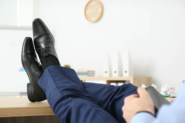 lazy office employee with mobile phone at workplace, closeup - business man shoes on desk imagens e fotografias de stock