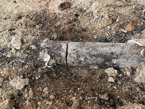 Scratched lead pipe, embedded in the ground
