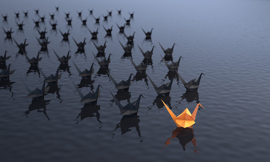 Leadership concept with an orange colored paper crane in the first place on the water. ( 3d render )