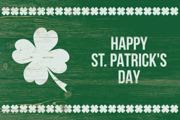 4 leaf clover and white text happy st. patrick's day over green wooden wall stock photo