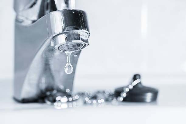 A leaking tap faucet dripping water in a sink stock photo