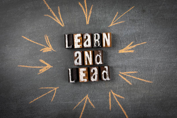 Learn and Lead. Letters of the alphabet with text on a dark chalk board stock photo