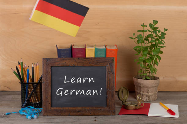 Learning languages concept - blackboard with text "Learn German", flag of the Germany, books, chancellery stock photo