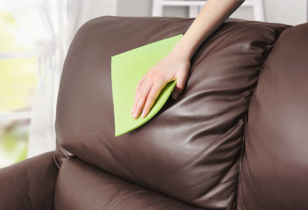 Leather sofa cleaning, woman's hand removes the dust with cloth from the firniture,clean the spot. 