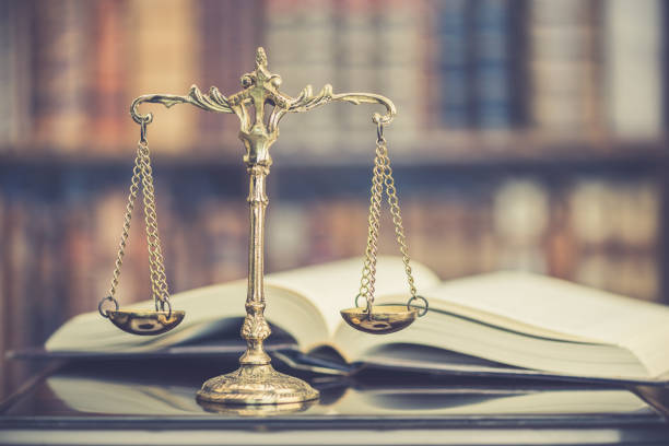 Legal office of lawyers, justice and law concept : Judge gavel or a hammer and a base used by a judge person on a desk in a courtroom with blurred weight scale of justice, bookshelf background behind. stock photo