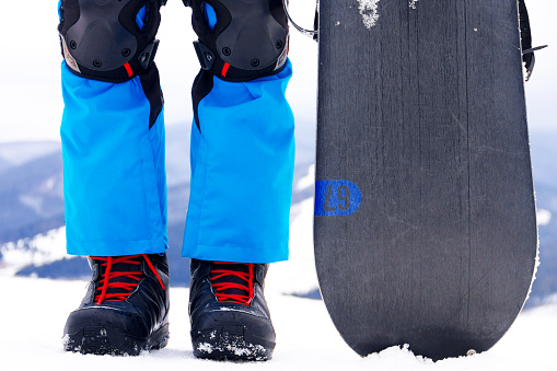 Legs in snowboarder boots with snowboard