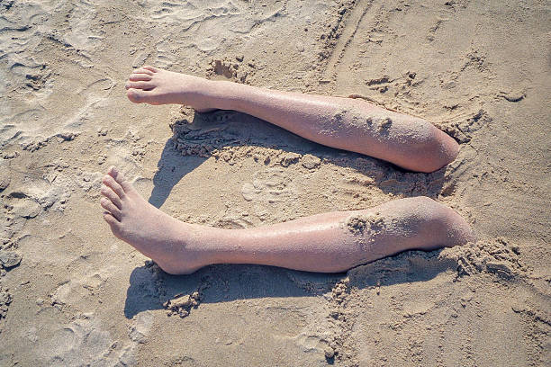 Legs of a boy in the sand of a beach Legs of a boy buried in the sand of a beach, vintage style human feet buried in sand. summer beach stock pictures, royalty-free photos & images