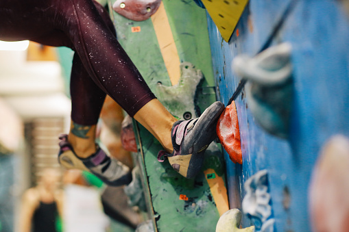 A close up of the legs at a boulder climbing wall. It's a popular exercise for building strength, tactics, determination, and stamina. Indoor boulder climbing makes a healthy hobby for active people.