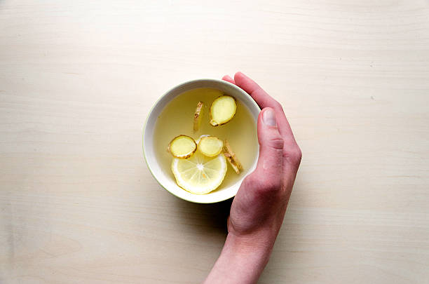 Lemon, cup of tea, light table, human hand. stock photo
