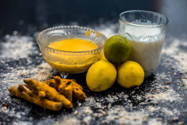 Lemon face mask on the wooden surface consisting lemon juice, gram flour or chickpea flour, turmeric or Haldi and milk in a glass bowl.For the treatment of tans. Lemon face mask on the wooden surface consisting lemon juice, gram flour or chickpea flour, turmeric or Haldi and milk in a glass bowl.For the treatment of tans. desi cosmetics stock pictures, royalty-free photos & images