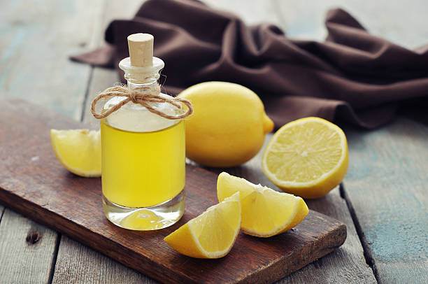 Lemon oil in a glass jar surrounded by lemons stock photo