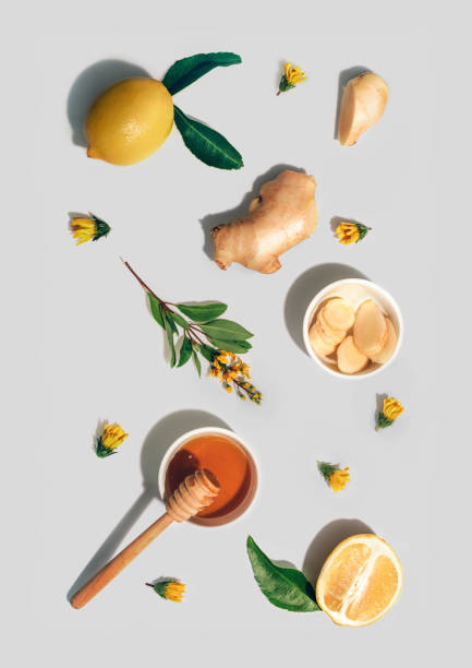 Lemon whole and cut out pieces, ginger, honey and yellow flowers pattern on light grey background. stock photo