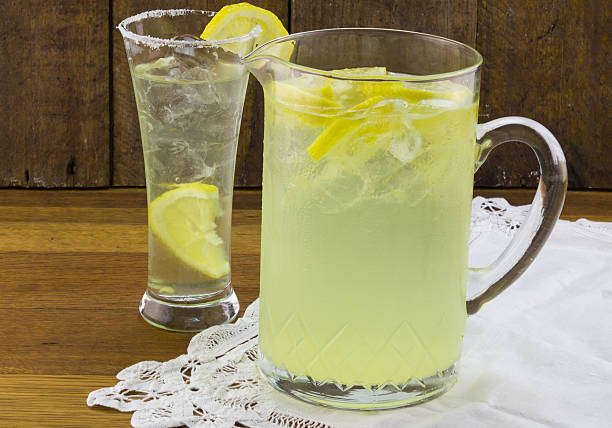 Lemonade in glass pithcher with glass and lemon slices stock photo