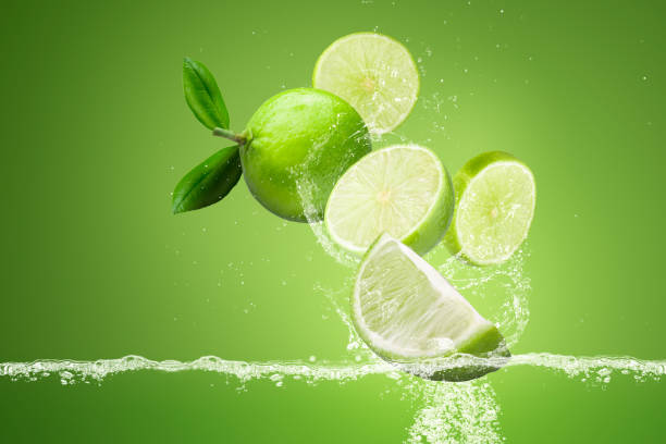 lemonade Splashing on Green lemon fruit isolated on Green background stock photo