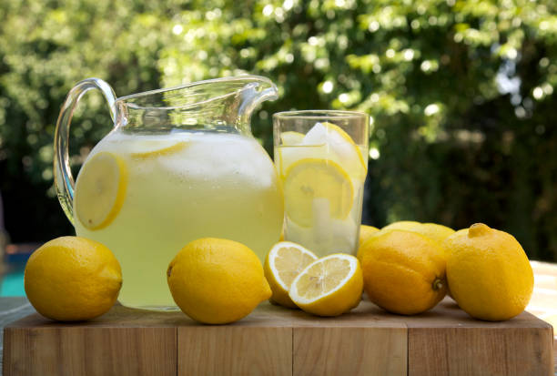 Lemons next to a pitcher and glass of fresh made lemonade  stock photo