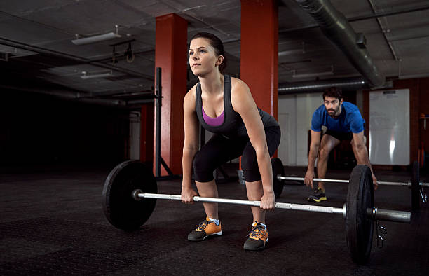 Less a routine, more a commitment to health Shot of fitness enthusiasts lifting barbells in the gym less weight stock pictures, royalty-free photos & images