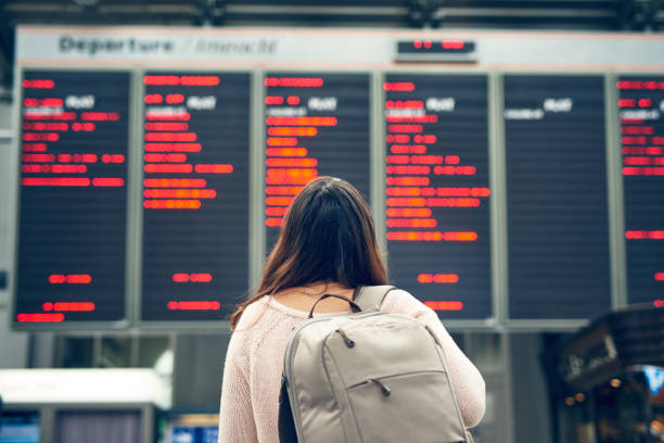 Let the journey begin Rearview shot of an unrecognizable young woman looking at an arrivals and departures board while standing in an airport irish women stock pictures, royalty-free photos & images