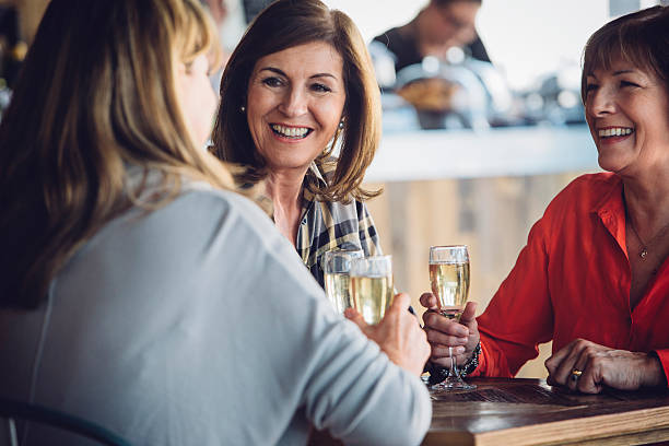 Let's Celebrate A small group of mature woman are drinking champagne together. They are chatting and socialising and look very happy. bar drink establishment stock pictures, royalty-free photos & images