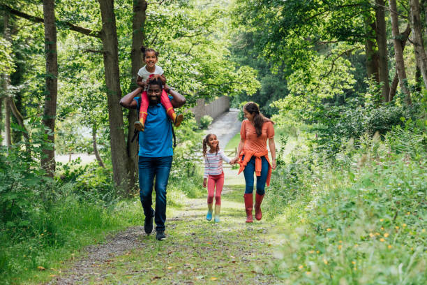 Let's Go Exploring! Happy family walking on a footpath through the woods in their wellies in Northumberland. northumberland stock pictures, royalty-free photos & images