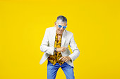 Funny and extravagant senior man in his sixties having fun and dancing on a colored background