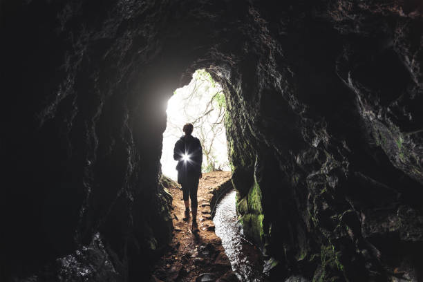 Levada Walk On Madeira Island Leavda walk on Madeira island. Woman with flashlight entering the tunnel. cave stock pictures, royalty-free photos & images