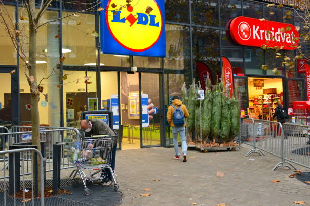Lidl German chain supermarket and Kruidvat in Leuven Belgium. Leuven, Vlaams-Brabant, Belgium - November 27, 2020: Lidl Belgium food supermarket chain in autumn. Facade Lidl and Kruidvat. Customers entering the supermarket. lidl stock pictures, royalty-free photos & images