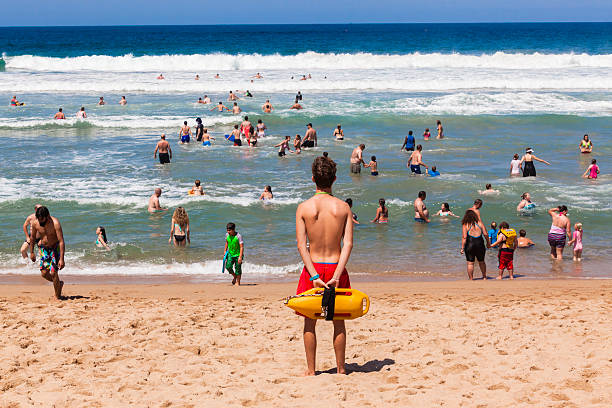 Lifeguard Beach Ocean Public Ramsgate South Coast, South Africa - October 4, 2015: Lifeguard with safety rescue swimming buoy watching public swim in ocean waves lifeguard stock pictures, royalty-free photos & images