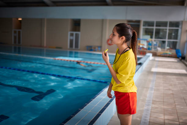 Lifeguard blowing whistle in indoor pool Close-up of female lifeguard blowing whistle in indoor pool lifeguard stock pictures, royalty-free photos & images