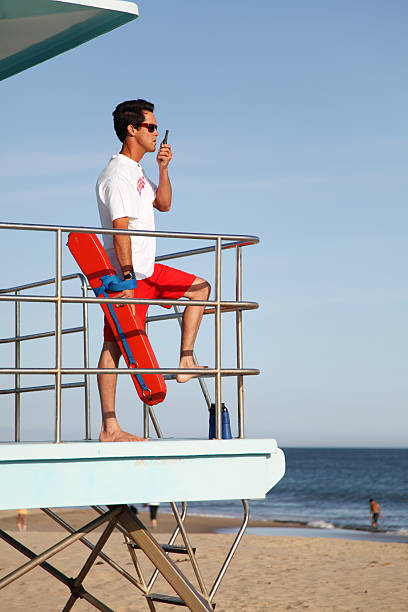 Lifeguard On The Radio Male lifeguard at the ocean beach. gchutka stock pictures, royalty-free photos & images