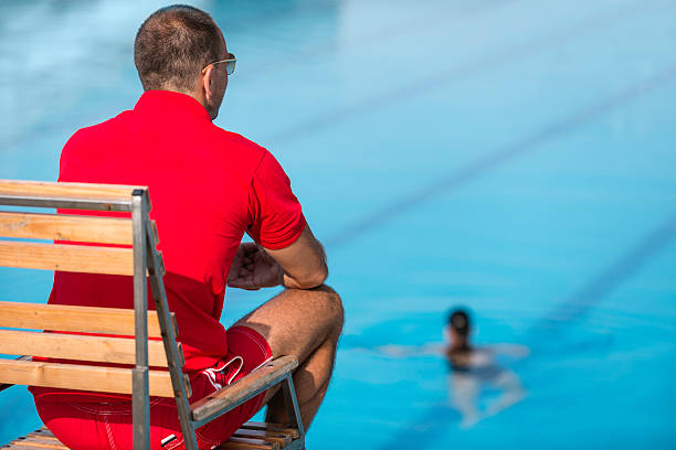 Lifeguard Lifeguard in chair, overlooking swimming pool lifeguard stock pictures, royalty-free photos & images