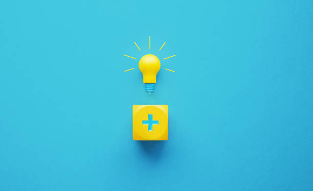 Light Bulb and Yellow Cube with Plus Sign Light bulb sitting above a yellow cube with plus sign on turquoise background. Innovation concept. Horizontal composition with copy space. plus sign photos stock pictures, royalty-free photos & images