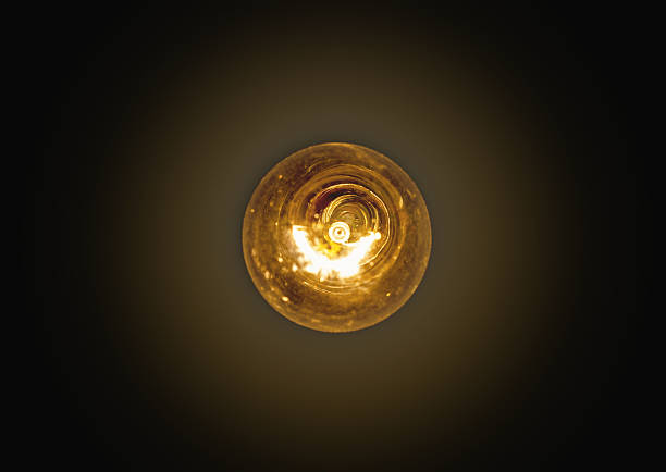 light bulb lit on a black background stock photo