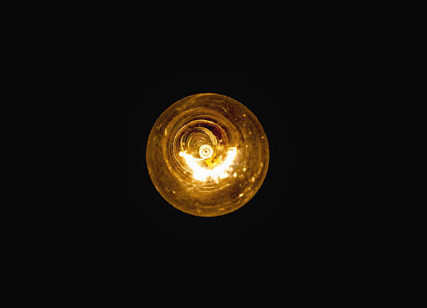 light bulb lit on a black background stock photo